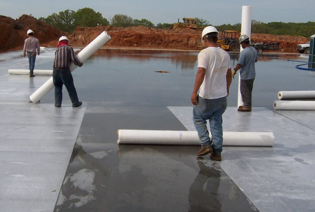 UltraCure NCF curing blanket being rolled out on a wet concrete slab